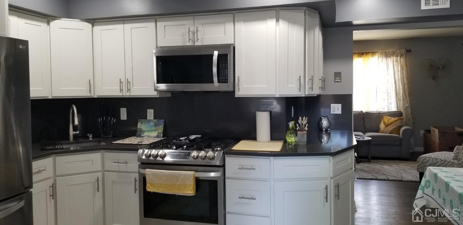 197 Evergreen Road, Unit 9A Edison, NJ 08837 - Photo 8 of 24 a kitchen with stainless steel appliances granite countertop a stove a sink and a microwave