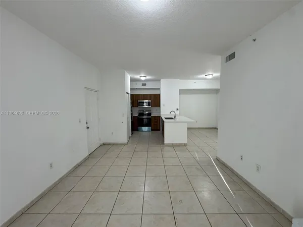 a view of empty room with open kitchen