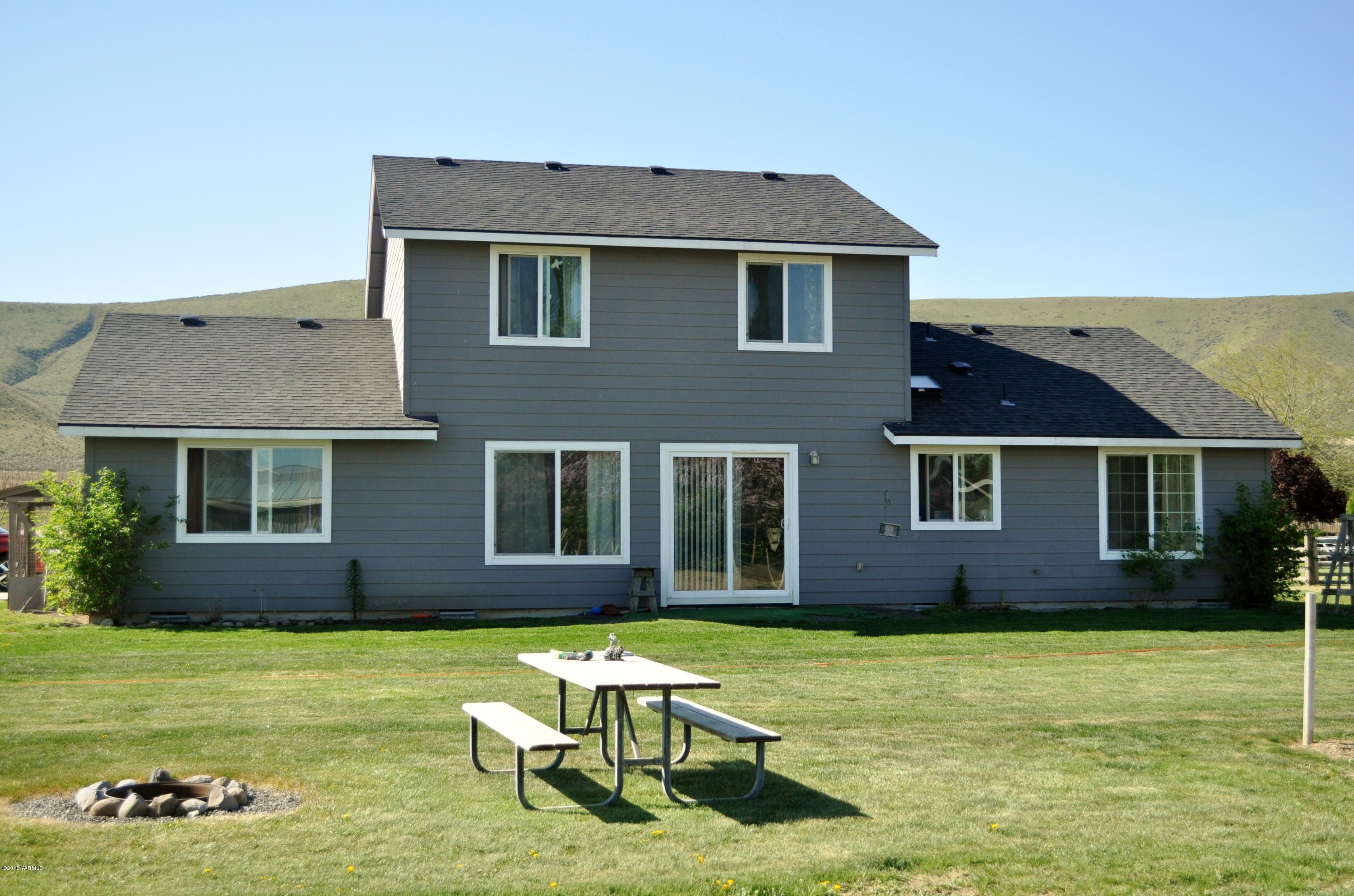 5011 Gamache Road Moxee, WA 98936 - Photo 2 of 26 a brick house with a yard chairs and a table and chairs