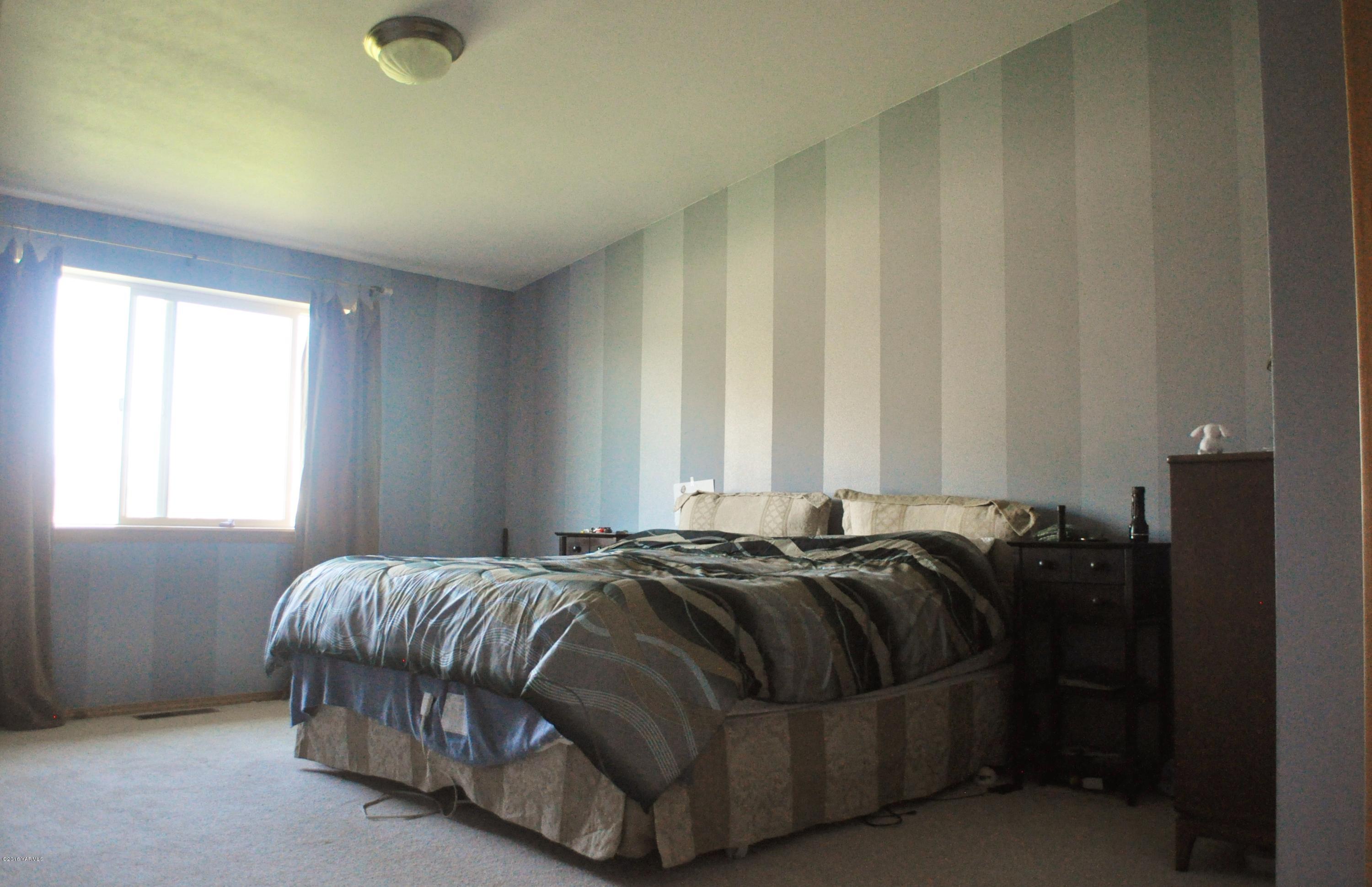 5011 Gamache Road Moxee, WA 98936 - Photo 10 of 26 a bed sitting in a bedroom next to a window