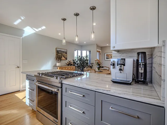 a kitchen with stainless steel appliances granite countertop a stove a sink and a white cabinets
