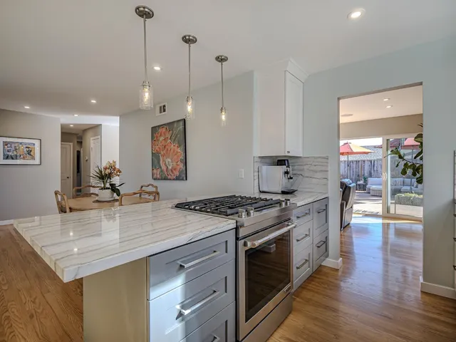 a kitchen with a stove a sink a counter space and wooden floor