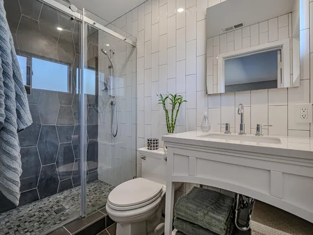 a bathroom with a sink toilet a mirror and shower