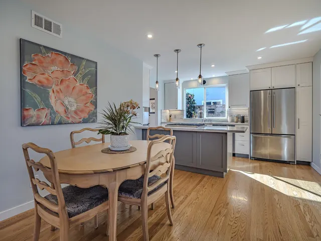 a kitchen with granite countertop a table chairs stainless steel appliances and wooden floor