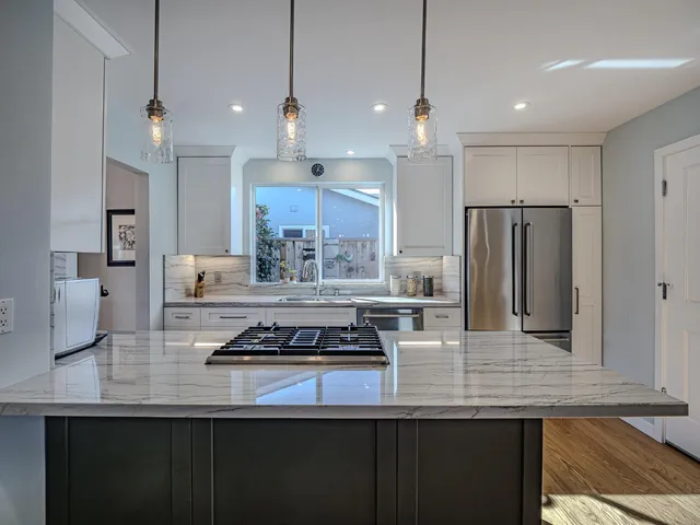 a kitchen with kitchen island stainless steel appliances a sink a stove a refrigerator and cabinets