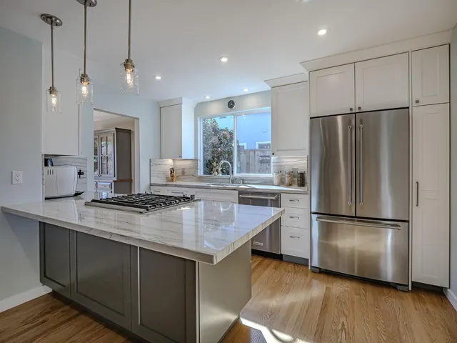 a kitchen with kitchen island a counter top a refrigerator a sink and a stove