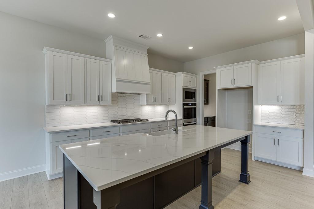 454 Thunder Road Buford, GA 30518 - Photo 17 of 78 a kitchen with kitchen island a counter space a sink and cabinets