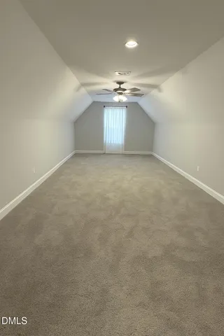 an empty room with a chandelier fan and windows