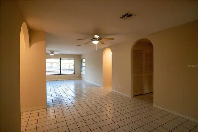 a view of an empty room with window and wooden floor