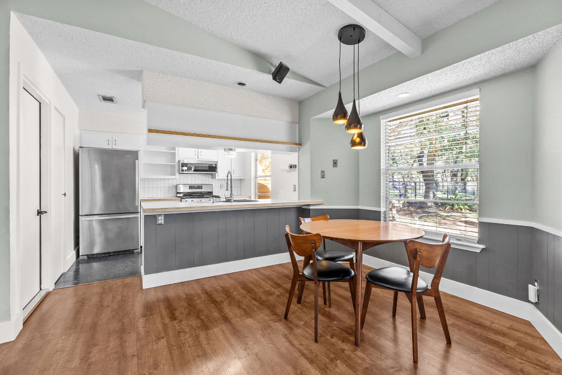1906 Parkside Lane Austin, TX 78745 - Photo 9 of 40 Dining area featuring a textured ceiling, a wainscoted wall, and dark wood-style flooring