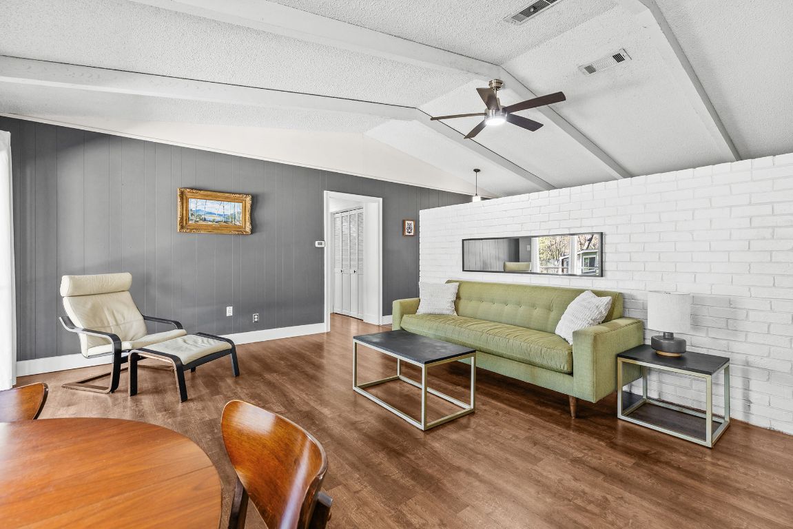 1906 Parkside Lane Austin, TX 78745 - Photo 2 of 40 Living area featuring a textured ceiling, brick wall, wood finished floors, ceiling fan, and wood walls