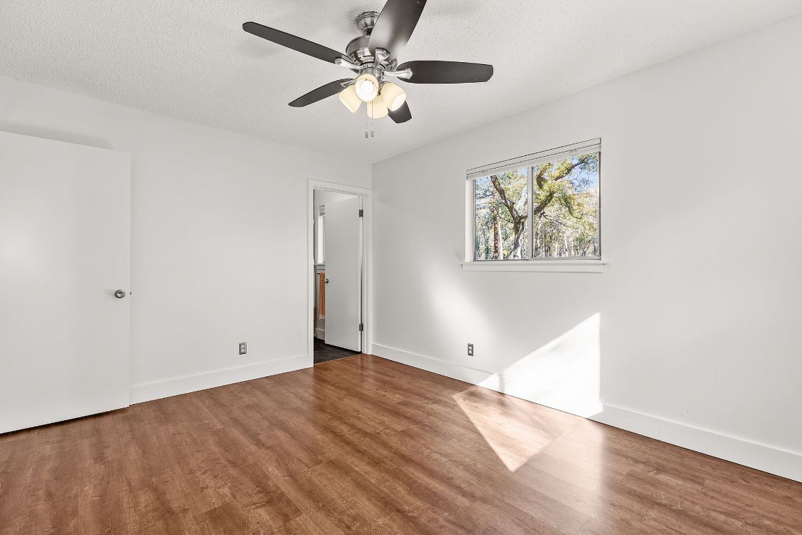 1906 Parkside Lane Austin, TX 78745 - Photo 19 of 40 Unfurnished bedroom featuring wood finished floors, a ceiling fan, and a textured ceiling