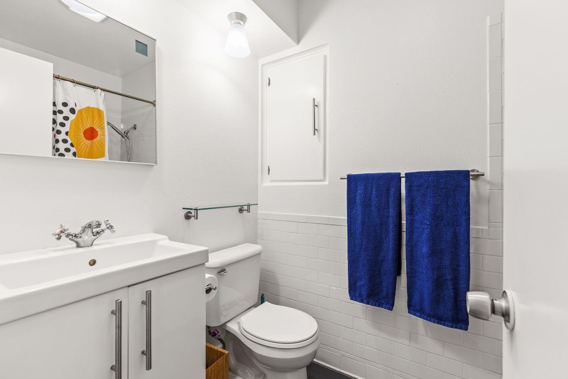 1906 Parkside Lane Austin, TX 78745 - Photo 24 of 40 Bathroom with vanity, tile walls, a shower with curtain, and a wainscoted wall