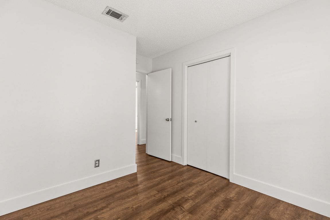 1906 Parkside Lane Austin, TX 78745 - Photo 25 of 40 Unfurnished bedroom with dark wood-style floors, a closet, and a textured ceiling