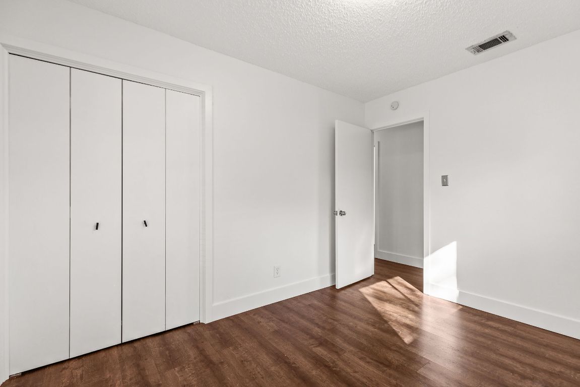 1906 Parkside Lane Austin, TX 78745 - Photo 28 of 40 Unfurnished bedroom featuring a closet, a textured ceiling, and dark wood finished floors