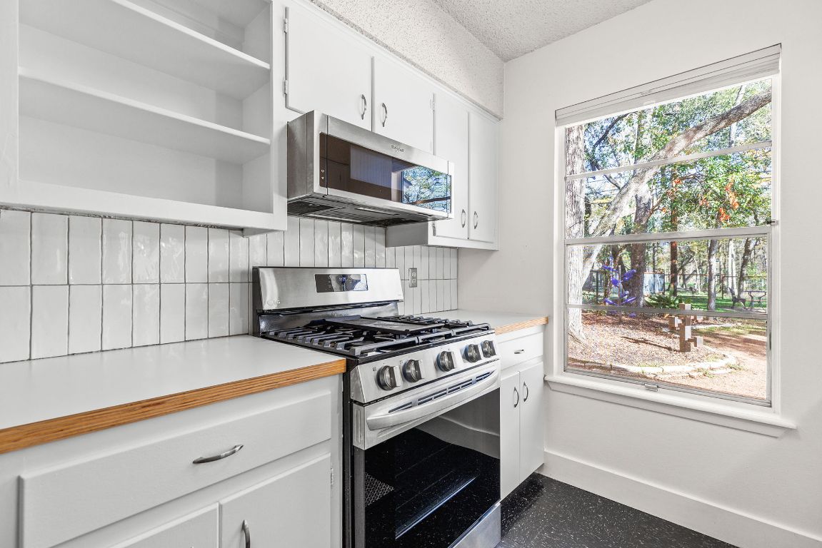 1906 Parkside Lane Austin, TX 78745 - Photo 7 of 40 Kitchen featuring open shelves, appliances with stainless steel finishes, white cabinets, light countertops, and a textured ceiling