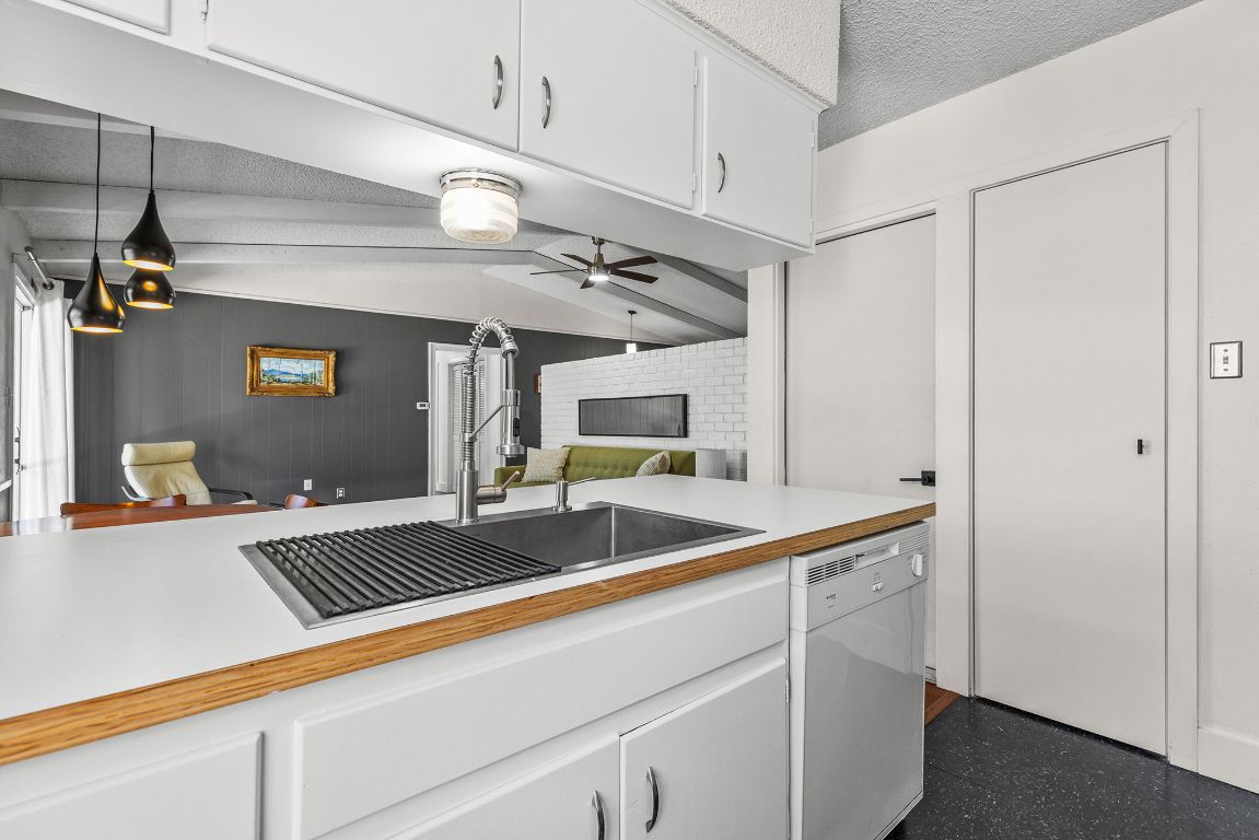 1906 Parkside Lane Austin, TX 78745 - Photo 40 of 40 Kitchen featuring white cabinetry, light countertops, open floor plan, dishwasher, and vaulted ceiling