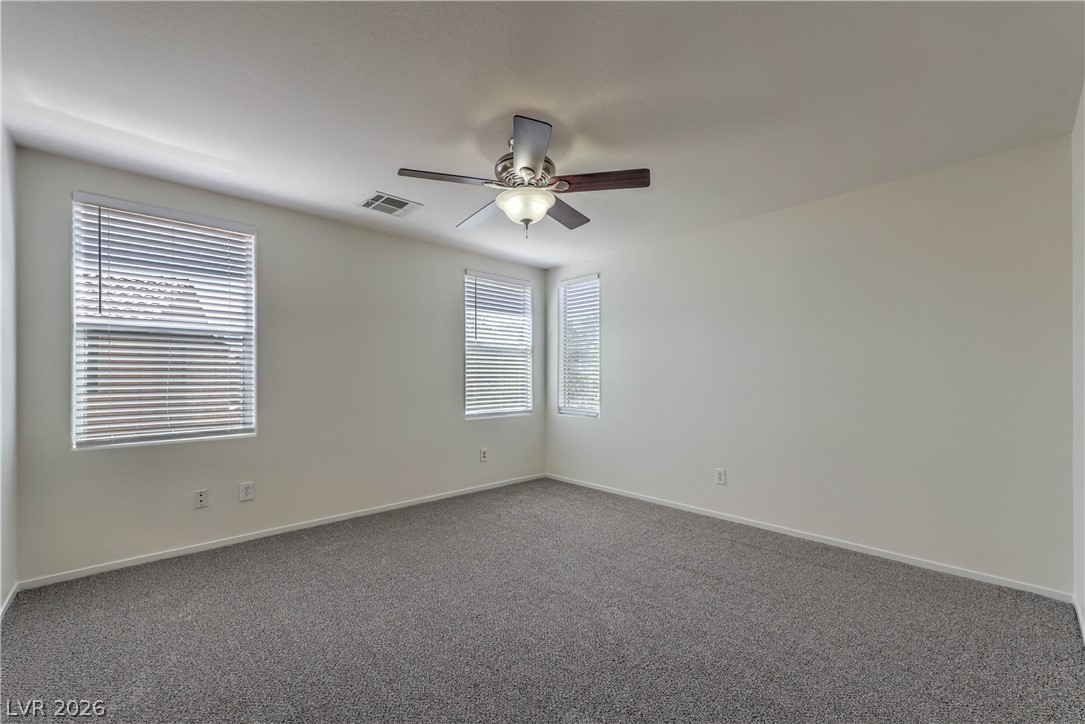 10939 Paradise Road Henderson, NV 89052 - Photo 22 of 36 A well-lit bedroom features plush carpeting and multiple windows for abundant natural light.