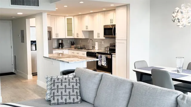 a kitchen with stainless steel appliances kitchen island granite countertop a refrigerator a stove a sink dishwasher with a dining table and chairs