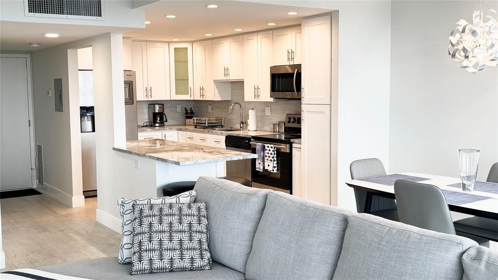 531 North Ocean Boulevard, Unit 1601 Pompano Beach, FL 33062 - Photo 4 of 32 a kitchen with stainless steel appliances kitchen island granite countertop a refrigerator a stove a sink dishwasher with a dining table and chairs