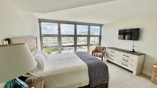 a bedroom with a bed a flat screen tv and a large window with the balcony view