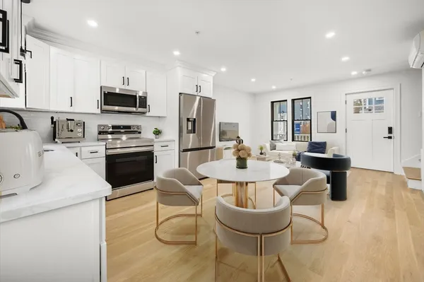 a kitchen with stainless steel appliances kitchen island granite countertop a sink a stove a kitchen island with chairs and white cabinets