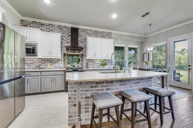 a kitchen with kitchen island granite countertop a table chairs sink and cabinets