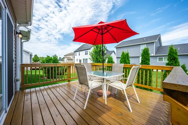 a view of a deck with table and chairs under an umbrella with wooden floor