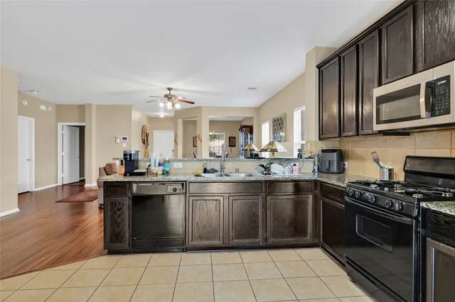 a kitchen with stainless steel appliances granite countertop a stove top oven a sink dishwasher and cabinets