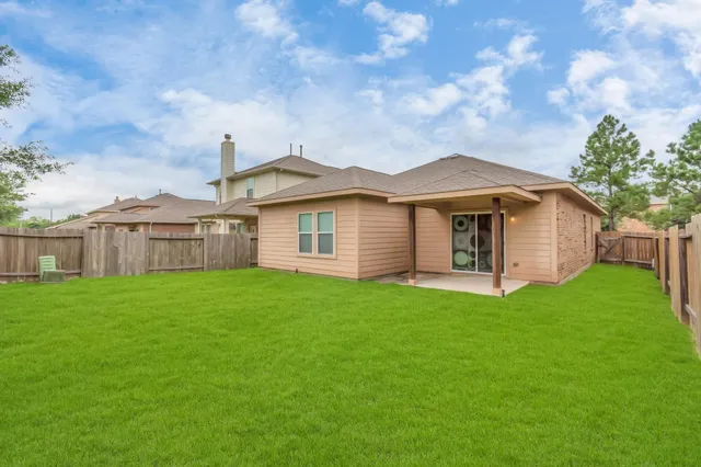a view of a yard in front of a house with plants and large tree