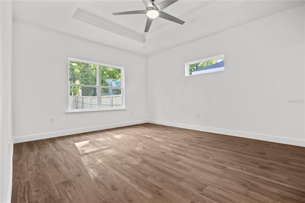 1086 Southwest 67th Drive Gainesville, FL 32607 - Photo 9 of 37 an empty room with wooden floor fan and windows