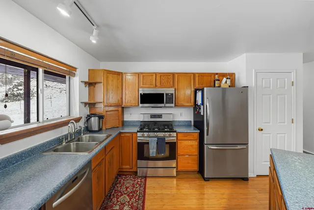 a kitchen with stainless steel appliances granite countertop a table chairs stove and refrigerator