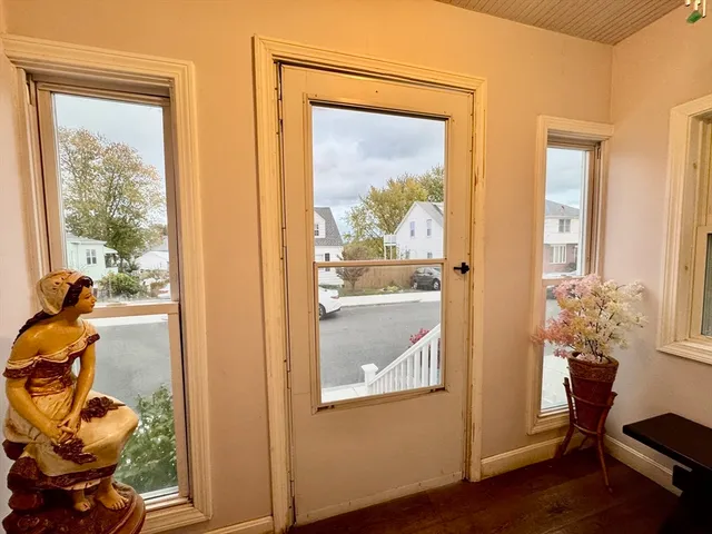 a view of a hallway with wooden floor and a livingroom with furniture