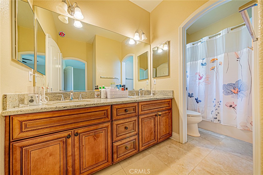 4088 Shady Ridge Circle Corona, CA 92881 - Photo 24 of 47 a bathroom with a granite countertop sink a toilet and a shower