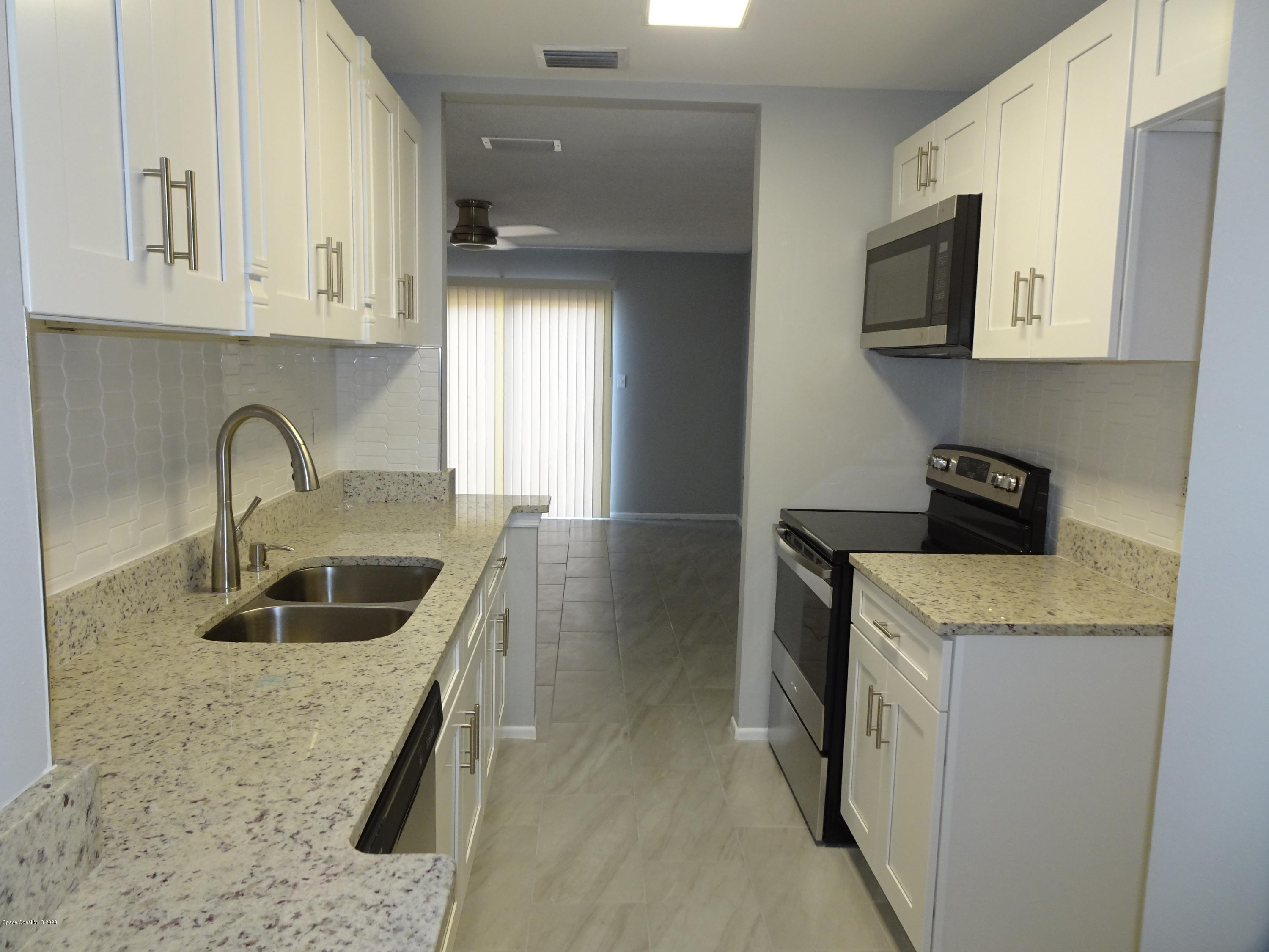 4875 Sisson Road Titusville, FL 32780 - Photo 3 of 14 a kitchen with granite countertop a sink a stove and cabinets