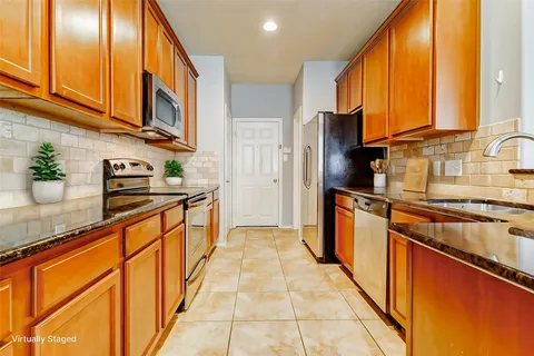 a kitchen with stainless steel appliances granite countertop a refrigerator a sink dishwasher a stove with wooden cabinets and floor