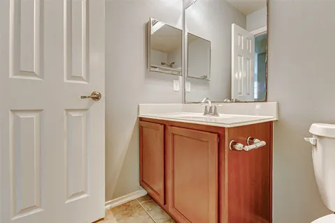 a view of a hallway with wooden floor and a bathroom