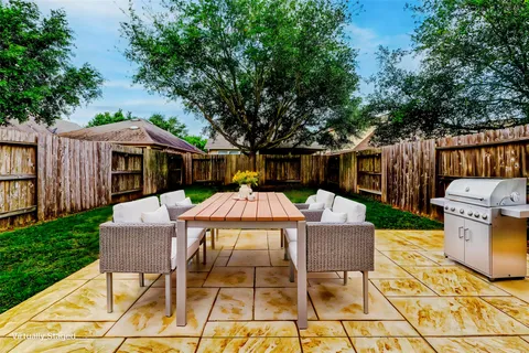 a backyard of a house with plants and large tree