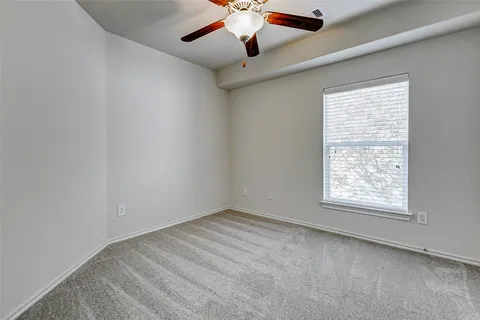 an empty room with a window and a fan