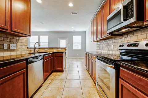 a kitchen with stainless steel appliances granite countertop a stove a sink and a microwave