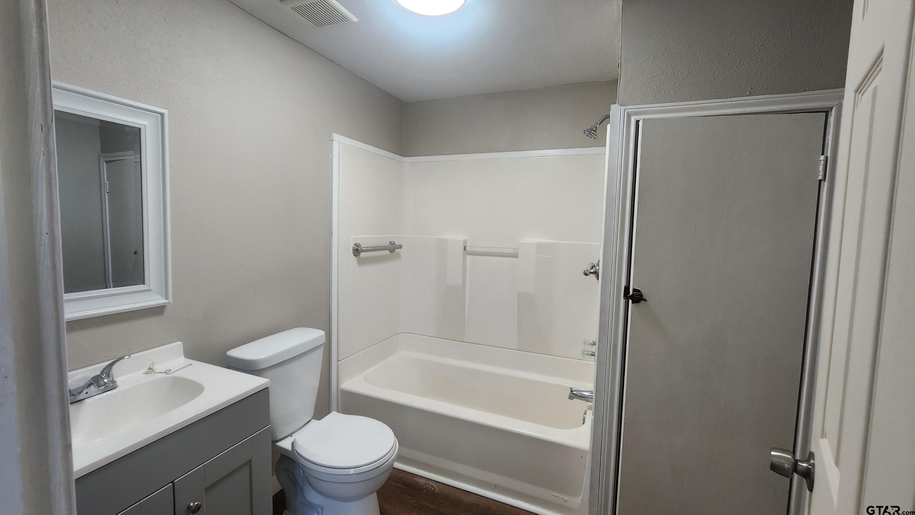 104 Carson Street Pittsburg, TX 75686 - Photo 5 of 9 a bathroom with a granite countertop toilet a sink and a bathtub