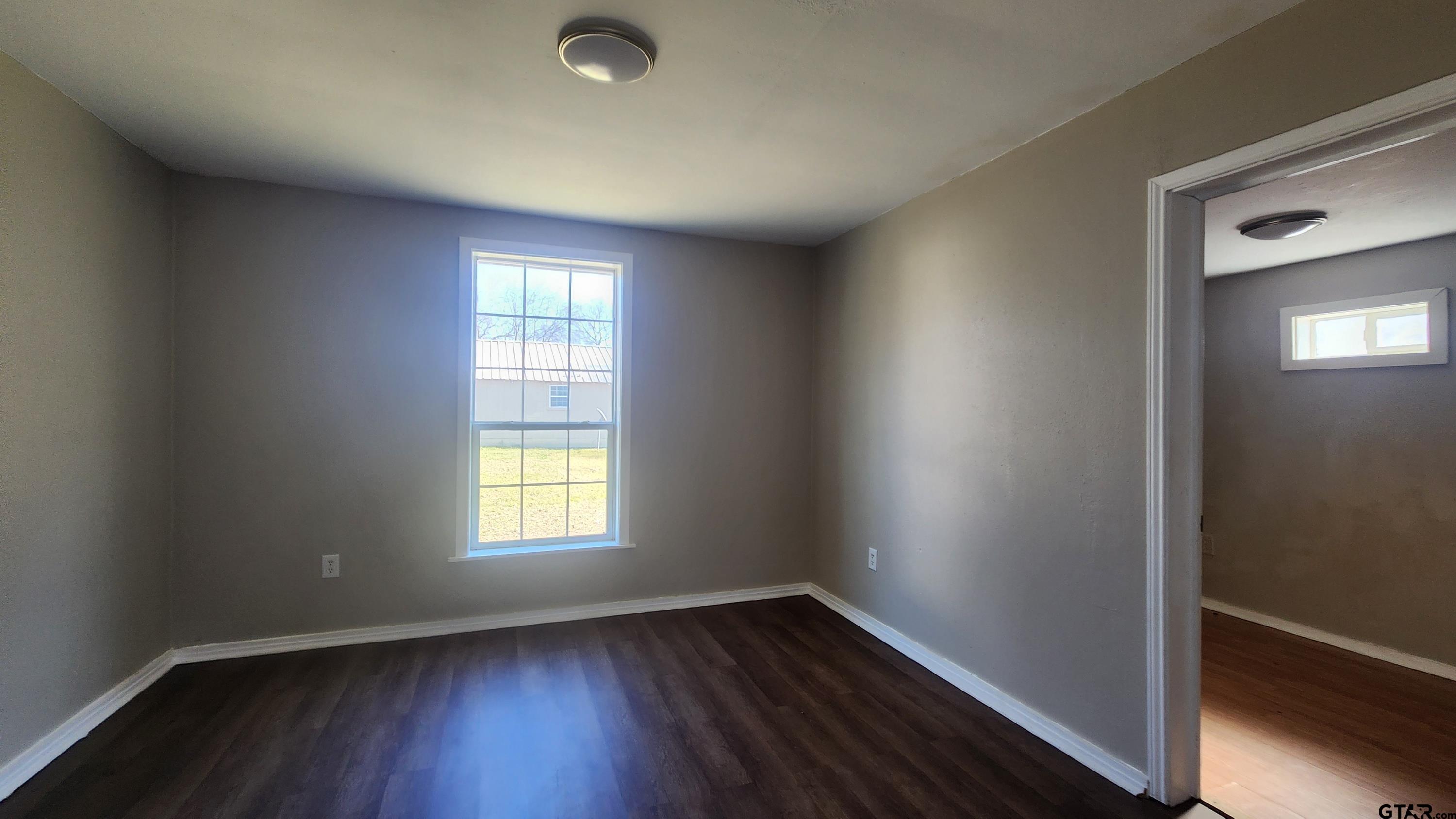 104 Carson Street Pittsburg, TX 75686 - Photo 8 of 9 an empty room with wooden floor and windows