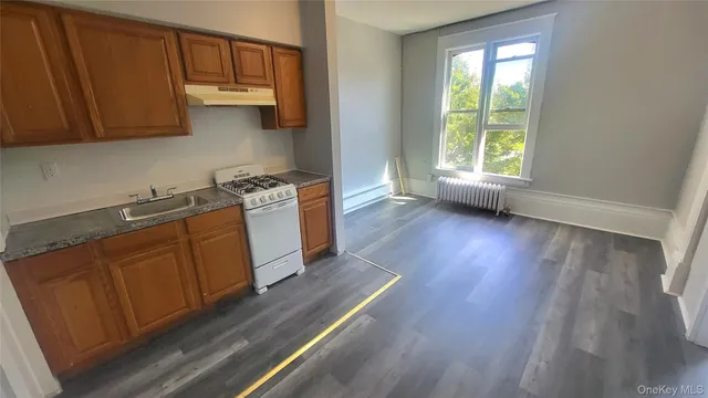 a kitchen with stainless steel appliances granite countertop a sink a stove a refrigerator cabinets and wooden floor