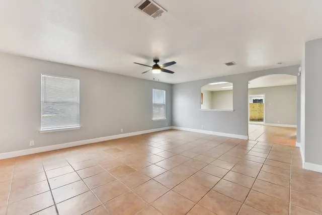 an empty room with windows and ceiling fan