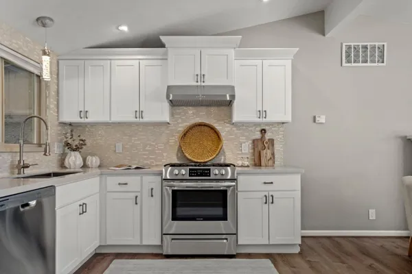 a kitchen with granite countertop white cabinets and stainless steel appliances