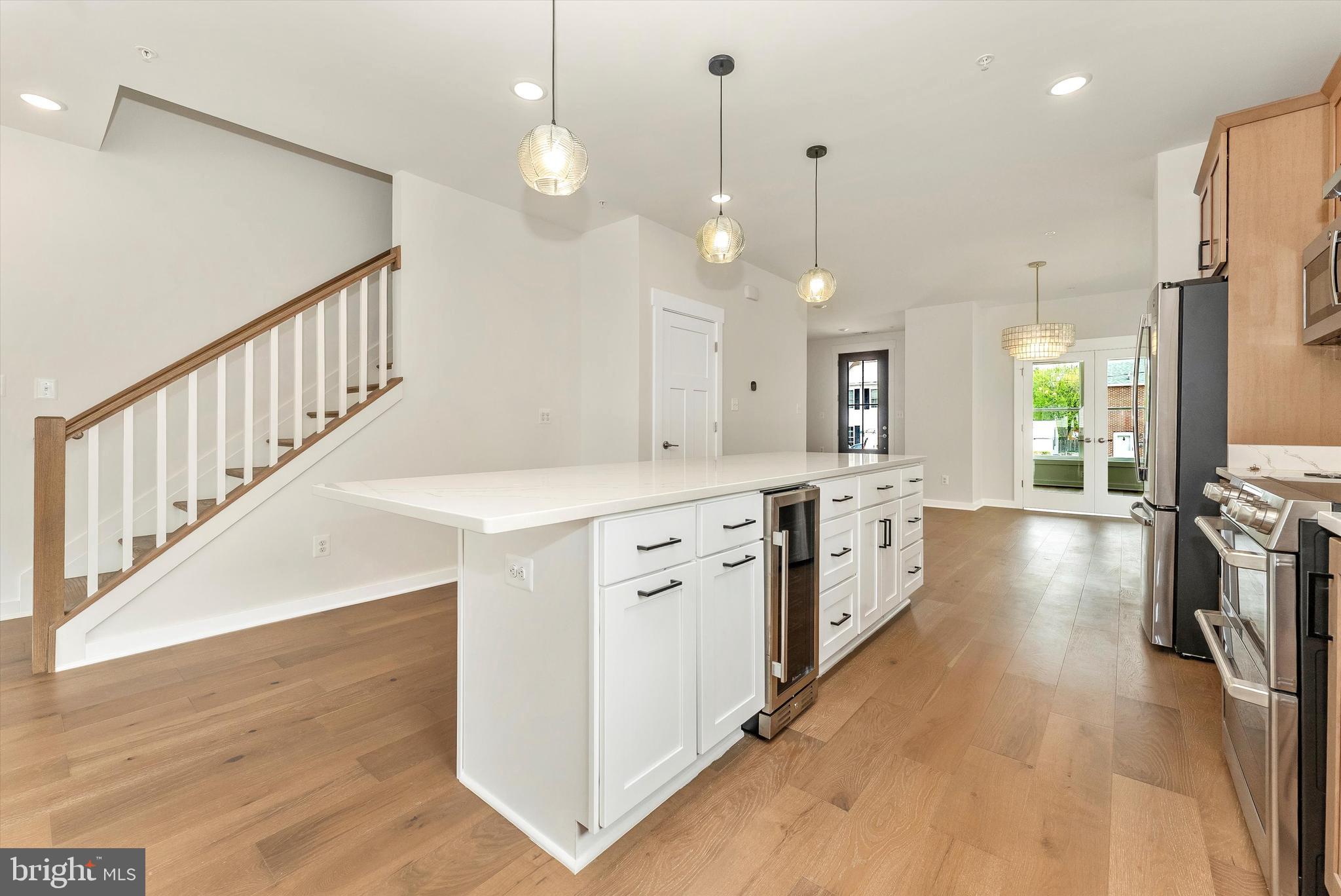 328 Madison Street Frederick, MD 21701 - Photo 15 of 49 a large white kitchen with a center island wooden floor and a view of living room