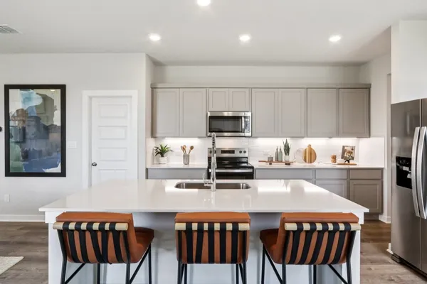 a kitchen with stainless steel appliances a table chairs microwave and refrigerator