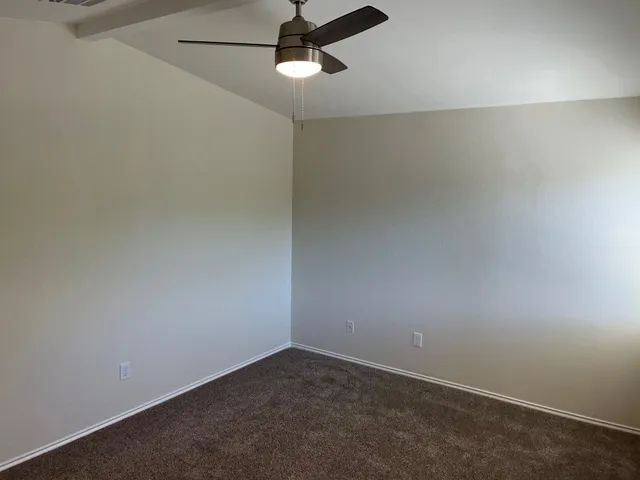 an empty room with a ceiling fan and carpet