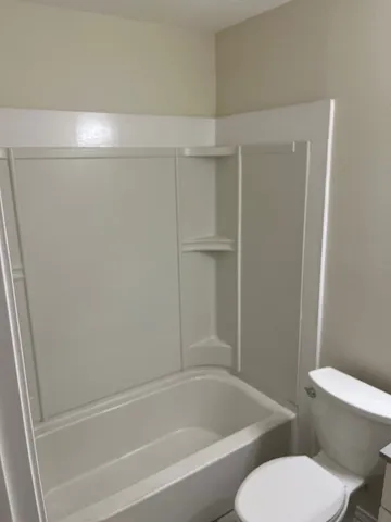 a white toilet sitting next to a bath tub