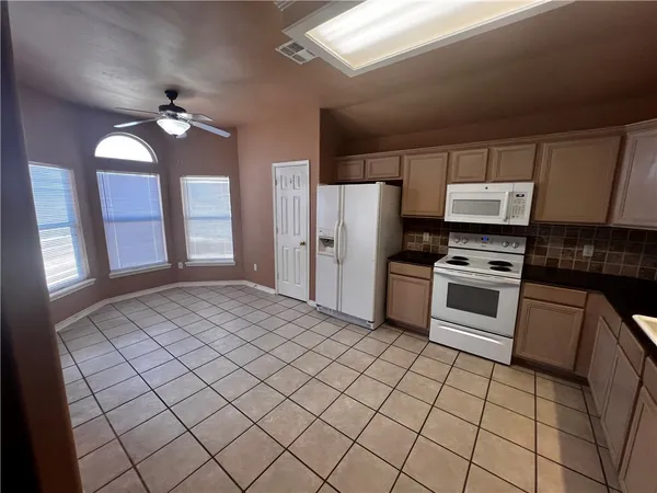 a kitchen with a stove a refrigerator and white cabinets